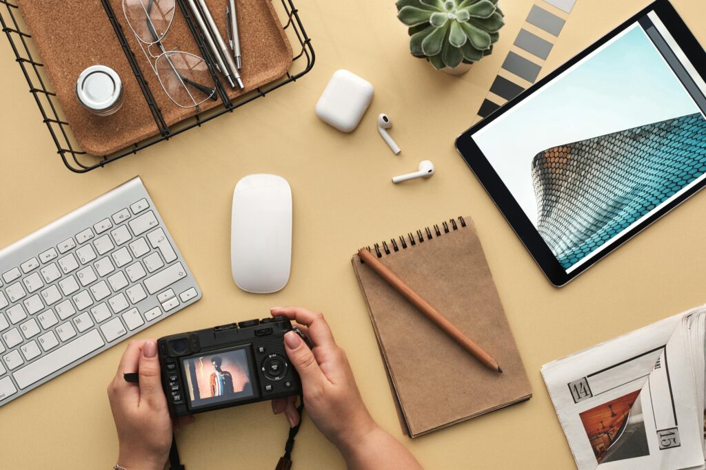 pexels-photo-3183132-3183132 Overhead view of a modern workspace featuring tech gadgets, a camera, and a notepad.
